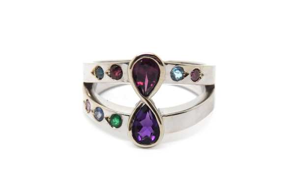 A family birthstone ring with parents in the eternal center setting and children and grand children on each band