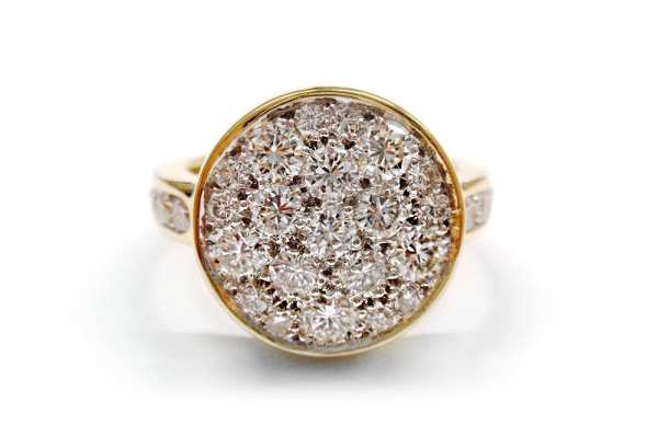 Multi sized round diamonds set into a round white gold disc framed in a yellow gold bezel ring