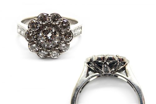 Diamond halo claw set engagement ring with a scalloped diamond outer border, with channel set princess cut shoulders
