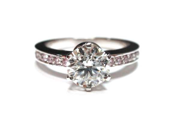 Six claw brilliant cut round diamond with pink diamonds pave set into band