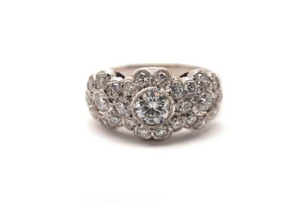 Brilliant cut round diamonds with surrounding smaller diamonds scalloped set with mill edging 